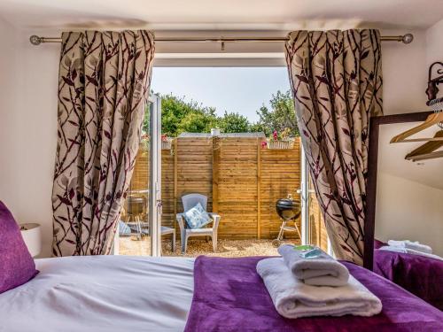 a bedroom with a bed with purple sheets and a window at Pass the Keys Charming Chalet A Stones Throw From The Beach in Chichester