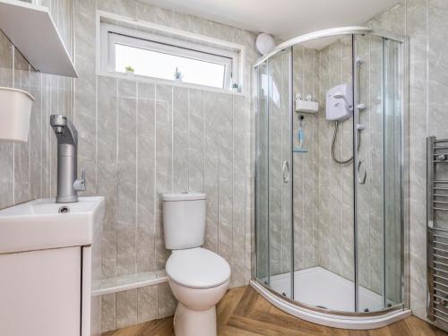 a bathroom with a shower and a toilet and a sink at Pass the Keys Charming Chalet A Stones Throw From The Beach in Chichester