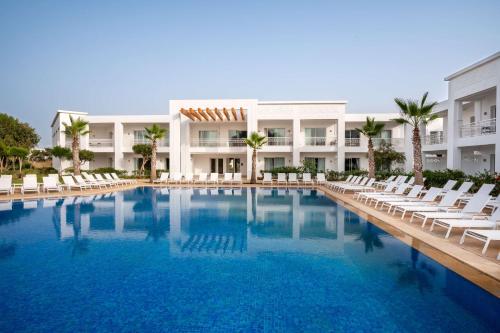 einen Pool mit Stühlen und ein Gebäude in der Unterkunft Radisson Blu Resort, Saidia Garden in Saidia 