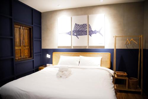 een slaapkamer met een groot wit bed met blauwe muren bij Tali-Yailai Hostel in Pattaya