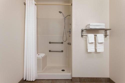 a bathroom with a shower and a toilet and towels at Baymont by Wyndham Hutchinson in Hutchinson