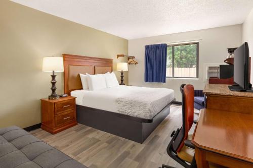 a hotel room with a bed and a desk with a computer at Baymont by Wyndham Hutchinson in Hutchinson