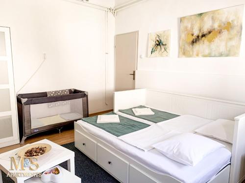 a bedroom with a white bed and a table at Matija Apartment in Novi Sad