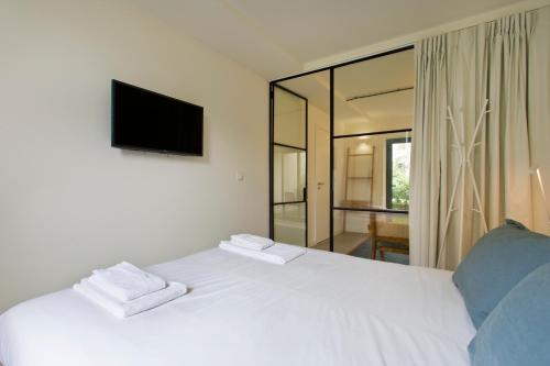 Schlafzimmer mit einem weißen Bett und einem TV an der Wand in der Unterkunft Zen Garden Studio D in Porto