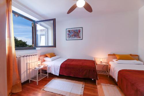 a bedroom with two beds and a window at Apartman Villa Marina in Rakalj