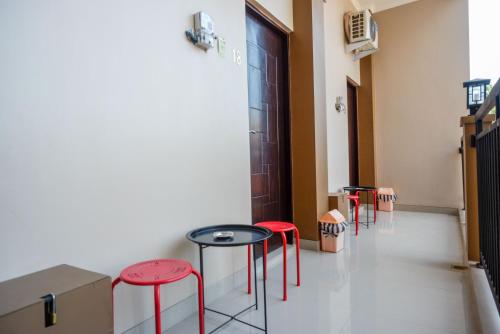 una stanza con sgabelli rossi, un tavolo e una porta di Urbanview Hotel Syariah John Sweet Home by RedDoorz a Tegal
