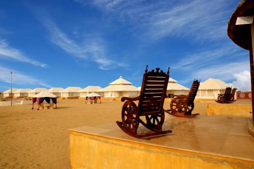 a couple of chairs on a beach with white tents at Bhavya Resort - Luxury Boutique Desert Camp in Jaisalmer