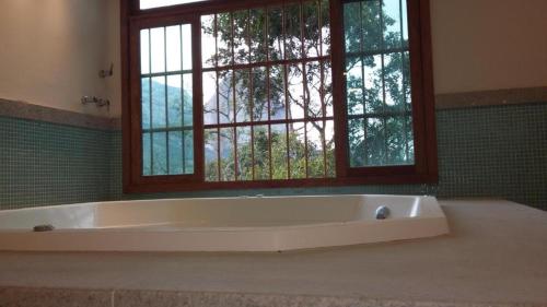 a bath tub in a bathroom with a window at Vista para Pedra Azul e TV de 85'' in Pedra Azul