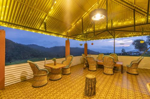 a restaurant with tables and chairs and a view of mountains at Zostel Homes Harabhag, Jogindernagar in Bīr