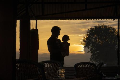 a man holding a child in front of a sunset at Zostel Homes Harabhag, Jogindernagar in Bīr