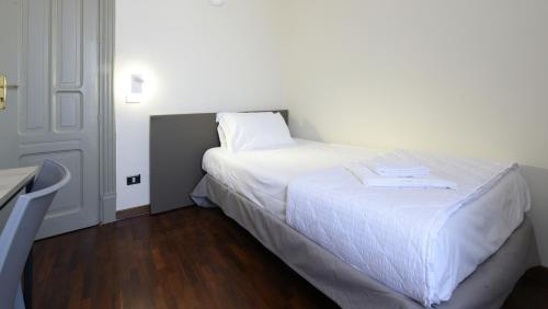 um quarto com uma cama branca e lençóis brancos em Hotel Roma 62 em Palermo