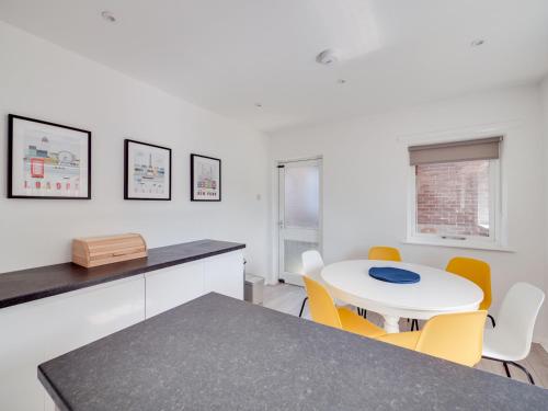 a kitchen with a white table and yellow chairs at Pass the Keys Lovely 3 Bedroom property golf club and parking in Manchester