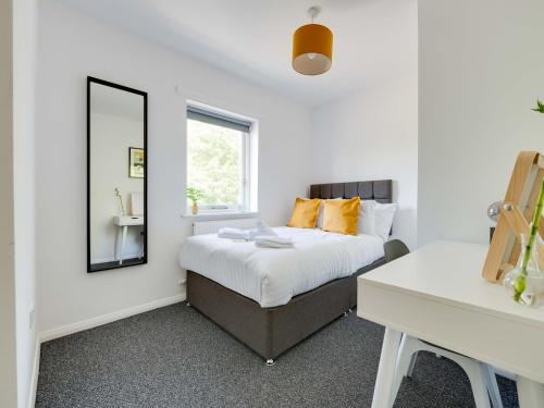 Schlafzimmer mit einem Bett, einem Spiegel und einem Schreibtisch in der Unterkunft Pass the Keys Lovely 3 Bedroom property golf club and parking in Manchester