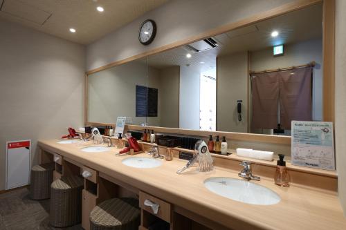 ein Badezimmer mit 3 Waschbecken und einem großen Spiegel in der Unterkunft Dormy Inn Okayama Natural Hot Spring in Okayama