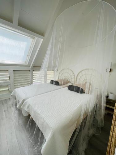 a bedroom with a large white bed with mosquito nets at Blue Lagoon, cottage les pieds dans l eau in Terre-de-Haut