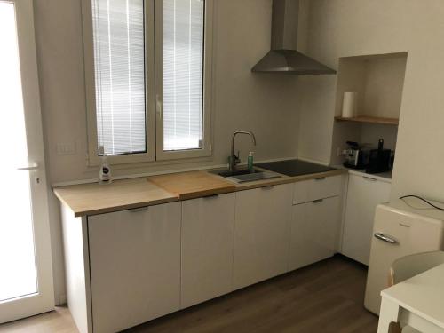 una cucina con armadi bianchi, lavandino e finestra di Cielo Apartment a Forlì