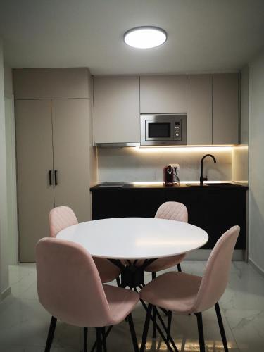 eine Küche mit einem weißen Tisch und rosa Stühlen in der Unterkunft Apartman Hobit in Opatija