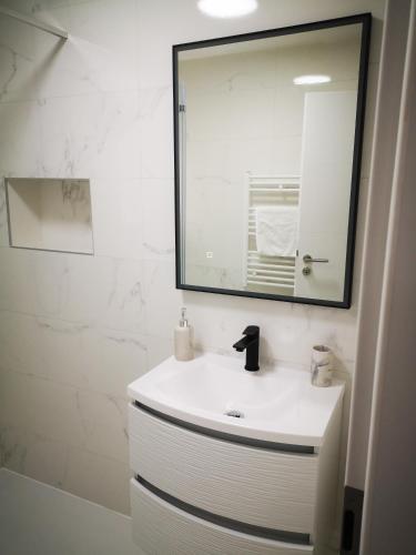 ein weißes Badezimmer mit einem Waschbecken und einem Spiegel in der Unterkunft Apartman Hobit in Opatija