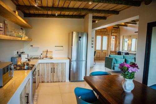 a kitchen with a wooden table and a refrigerator at De Uijlenes in Gansbaai