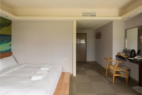 a bedroom with a bed and a desk and a table at Meci Hotel in Hualien City