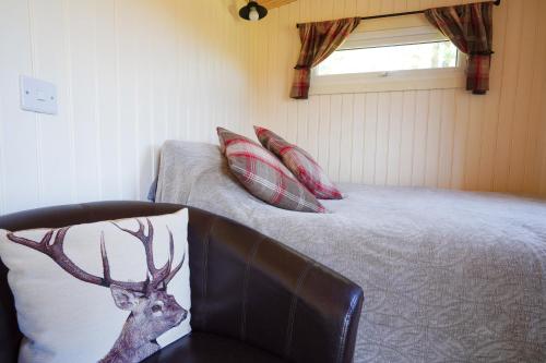 a bedroom with a bed and a chair with a deer pillow at The Laburnum Retreat Shepherd Hut private hot Tub in Upper Hulme