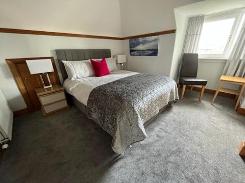 a bedroom with a large bed with red pillows at Pinewood Country House in Leuchars