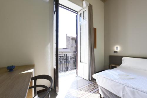 a small bedroom with a bed and a balcony at Hotel Roma 62 in Palermo