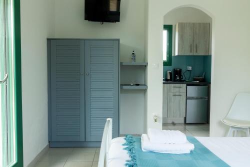 1 dormitorio con puerta azul y cocina en ANCIENT MEROPIA - Les jardins des muses en Apollonía