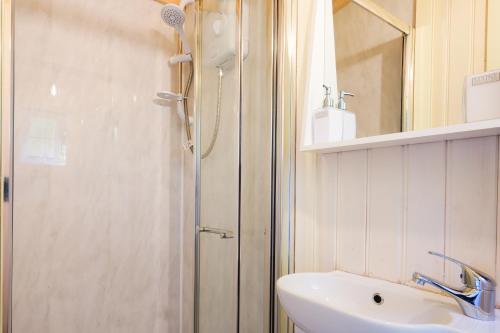 a bathroom with a shower and a sink and a mirror at The Laburnum Retreat Shepherd Hut private hot Tub in Upper Hulme