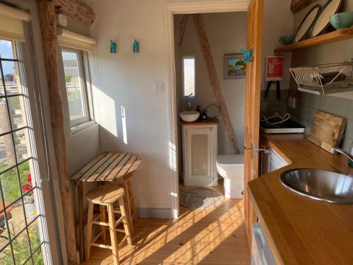 uma pequena cozinha com um lavatório e um balcão em The Hat's Hut em Mixbury
