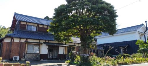 dom z drzewem przed nim w obiekcie 越前ゲストハウスTAMADA w mieście Sakai