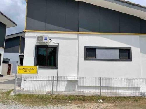 a white building with a yellow sign in front of it at Inderaloka Villa 23A Free Parking in Shah Alam