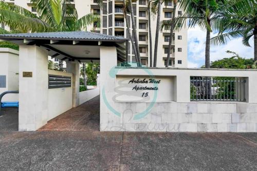 a sign in front of a building with palm trees at ZEN AT ARKABA 3BR Luxury Waterfront Apt Pool + BBQ in Darwin
