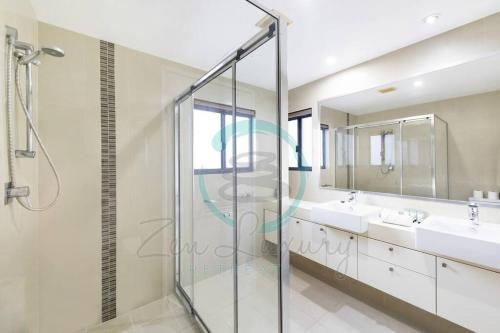 een badkamer met 2 wastafels en een glazen douchecabine bij ZEN AT ARKABA 3BR Luxury Waterfront Apt Pool + BBQ in Darwin