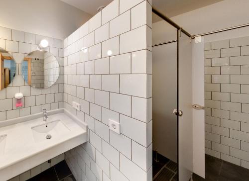 uma casa de banho em azulejos brancos com um lavatório e um chuveiro em The Nomad Hostel&Pension em Sevilha