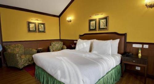 a hotel room with a large bed and chairs at Mayfair Darjeeling in Darjeeling