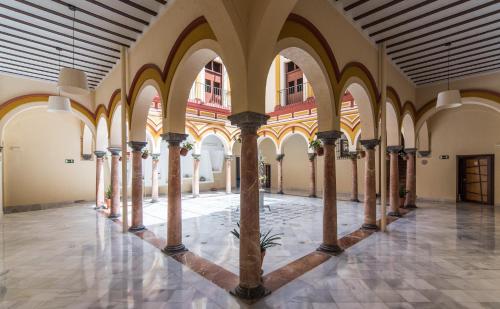 an arcade with columns and arches in a building at Hotel Palacio Marqués de Arizón in Sanlúcar de Barrameda