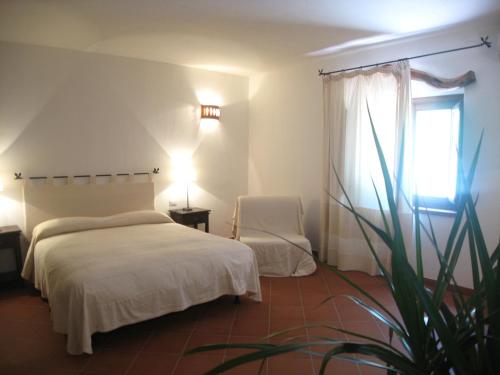 een slaapkamer met een bed, een stoel en een raam bij Il Vecchio Ginepro in Arzachena