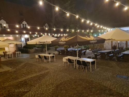 a patio with tables and umbrellas at night at Hotel Zajazd Kultury, dawniej Pocztowy in Zielona Góra