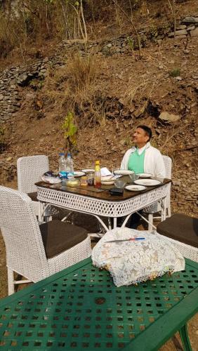 a man sitting at a table with a plate of food at Samira's Birds & Butterflies Park-Spashram Ganga Beach Retreat in Rishīkesh