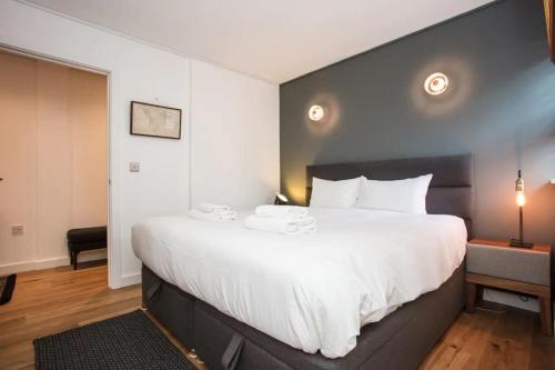Stunning 1 Bedroom Apartment nearby Borough Market في لندن: غرفة نوم بسرير كبير مع شراشف بيضاء