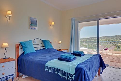 a bedroom with a blue bed and a large window at Casa dos Sonhos by Portucasa in São Brás de Alportel