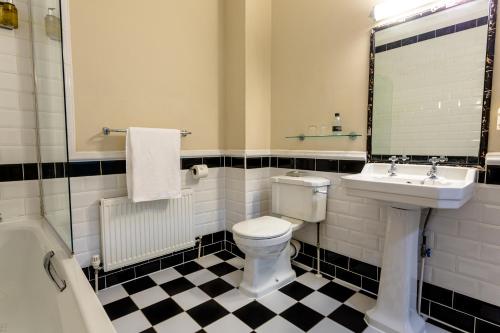 a bathroom with a toilet and a sink and a mirror at Woodland Manor Hotel in Bedford