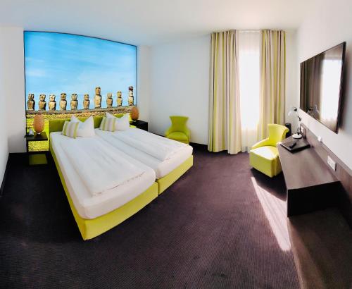 フルダにあるシティホテル  ヘシシャー ホフの大型ベッドとテレビが備わるホテルルームです。