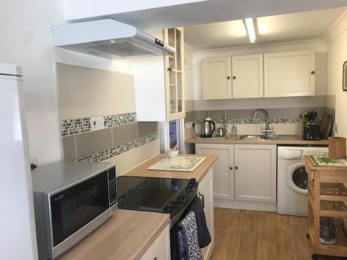 a kitchen with white cabinets and a counter top at Cosy comfortable Slice of Heaven Annex in Porlock in Porlock