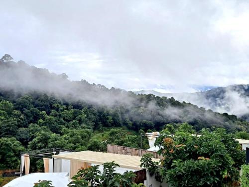 a house in front of a mountain with clouds at Phu Morinn Cafe &Camping Monjam in Mon Jam