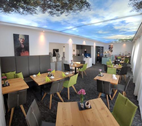 um restaurante com mesas de madeira e cadeiras verdes em CityHotel Hessischer Hof em Fulda