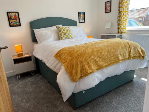 a bedroom with a green bed with a yellow blanket at Pass the Keys By the Beach Brand New Holiday home in Littlestone-on-Sea