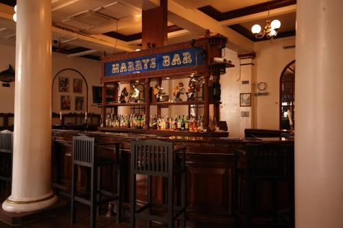 a bar with chairs and a counter with alcohol bottles at Cocoa Luxury Resort, Nyali, Mombasa in Mombasa