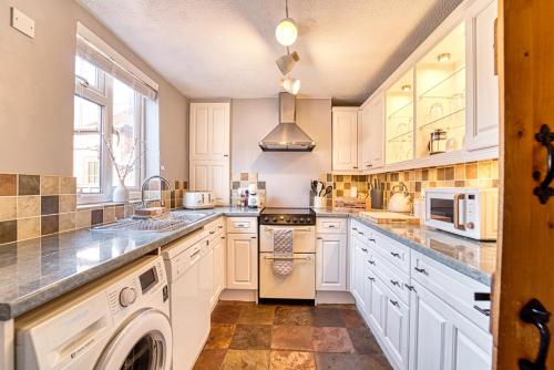 a kitchen with white cabinets and a washer and dryer at Guest Homes - London Road Cottage in Worcester